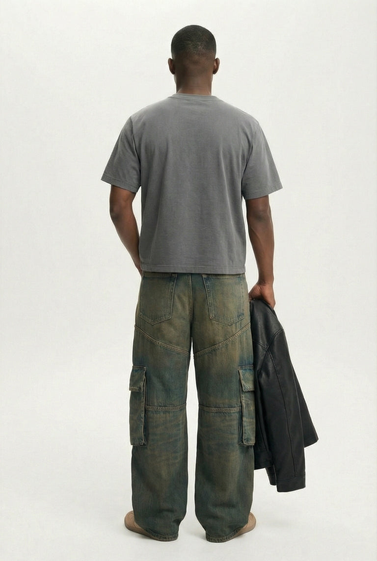 Person wearing a gray t-shirt and green cargo pants holding a black jacket on a white background